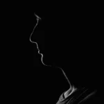 تصویر سیاه و سفید از نیمرخ فردی در تاریکی، مرتبط با کافه ترانه و آهنگ جدید