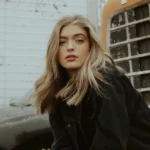 تصویر زنی جوان با موهای بلوند در کنار ماشین قدیمی، مناسب برای کافه ترانه و آهنگ جدید