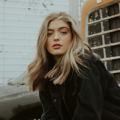 تصویر زنی جوان با موهای بلوند در کنار ماشین قدیمی، مناسب برای کافه ترانه و آهنگ جدید