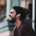 مردی با موهای بلند و ریش خندان در فضای باز، کافه ترانه، آهنگ جدید
