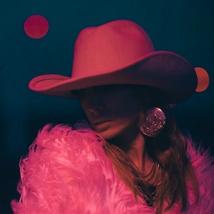 شخصی با کلاه صورتی و لباس پرزدار در نور کم، مرتبط با موزیک ویدئو و آهنگ جدید